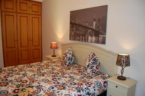 a bedroom with a bed with a comforter and two lamps at Villa Monte Alegrete with sea view in Santa Bárbara de Nexe