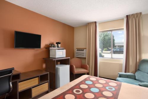 a hotel room with a bed and a tv and a chair at Super 8 by Wyndham Carbondale in Carbondale