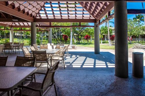 a patio with tables and chairs under a pavilion at Fairways402 in Waikoloa
