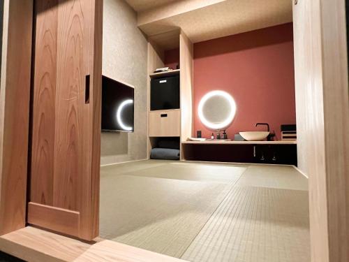 une porte ouverte menant à une chambre aux murs roses dans l'établissement FUMAI sauna &INN-遠赤外線サウナ-松江の歴史と文化と共に過ごすsmart hotel, à Matsue