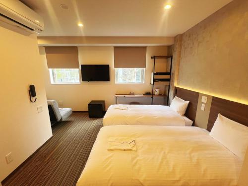 a hotel room with two beds and a flat screen tv at Nplus HOTEL Tokyo Nihonbashi in Tokyo