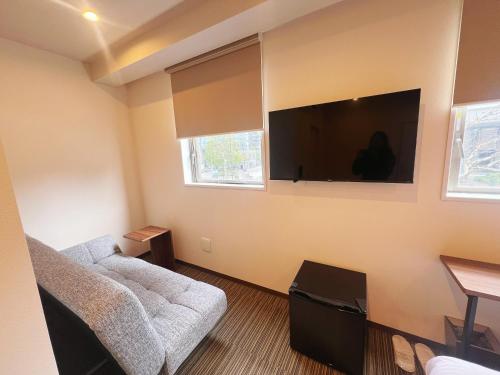 a living room with a couch and a flat screen tv at Nplus HOTEL Tokyo Nihonbashi in Tokyo