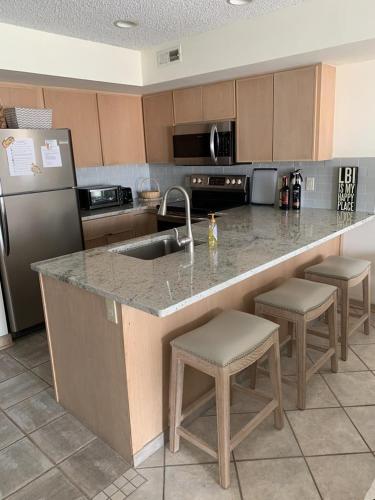 a kitchen with a sink and a counter with stools at Perfect Bayfront Condo With Beautiful Views Of The Bay in Beach Haven