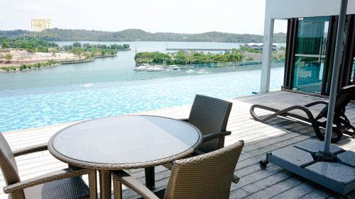 a table and chairs on a deck with a view of the water at Marina Puteri Harbour Johor by Perfect Host in Nusajaya