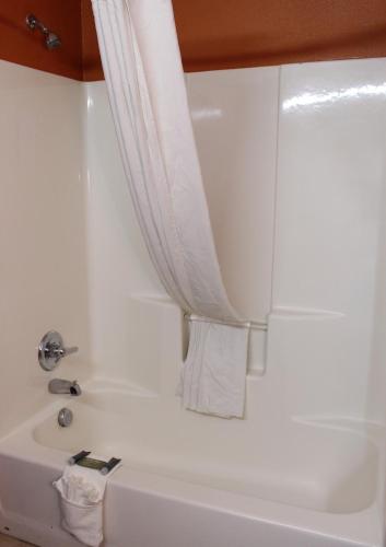 a white bath tub with a shower curtain at Scottish Inns Killeen near Fort Cavazos in Killeen