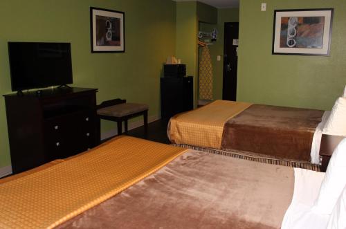 a hotel room with two beds and a flat screen tv at Scottish Inns Killeen near Fort Cavazos in Killeen