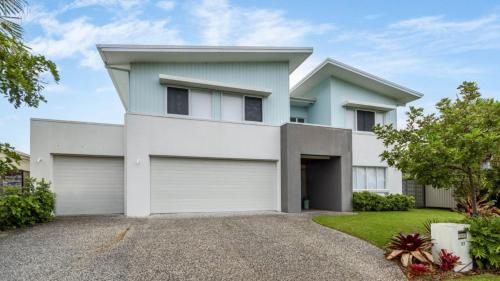 a white house with two garage doors at Luxury & Style On The Canal in Banksia Beach