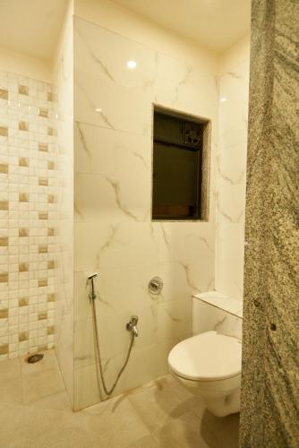 a white bathroom with a toilet and a window at Hotel Pride Inn Shirdi in Shirdi
