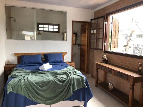 Schlafzimmer mit einem Bett mit blauer Bettwäsche und einem Fenster in der Unterkunft Pousada Chácara da Índia in Itatiaia