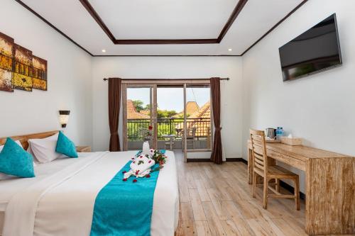 a bedroom with a bed and a desk and a window at La Sari Village in Canggu