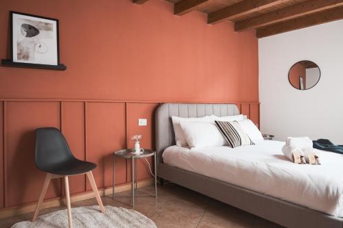 1 dormitorio con paredes de color naranja, 1 cama y 1 silla en DUPLEX con VISTA e TERRAZZA [6 minuti dal Bernina Express], en Tirano