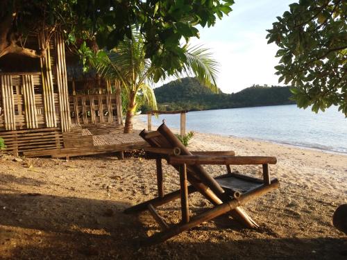 a bench on a beach next to a hut at Olivers Binucot Beach House in Romblon