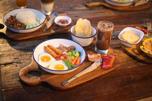 a wooden table with a plate of food with eggs and vegetables at ปิติฟาร์มมิลี่ คาเฟ่&แกลมปิ้ง ผามออีแดง in Ban Phumsaron