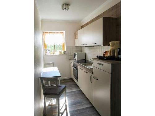 a kitchen with white cabinets and a table and a chair at In the Szczecin Lagoon Nature Park in Ueckermünde