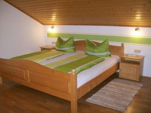 una camera con letto in legno e cuscini verdi di Holiday apartment Tulpe Schuniglhof 