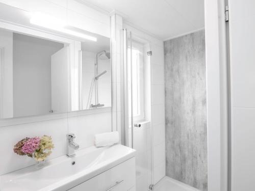 a white bathroom with a sink and a mirror at House in Zeeland near the Dyke in Wemeldinge