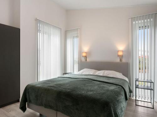 a white bedroom with a bed and two windows at Chalet in Zeeland by Scenic Pond in Wemeldinge