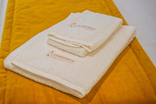 3 toallas sentadas encima de una cama en Batalha - Ferreiras Apartment en Batalha