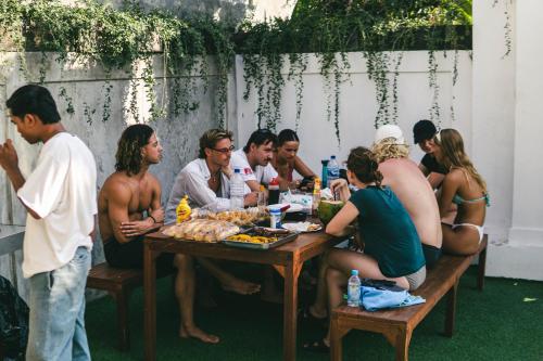 Eine Gruppe von Menschen, die an einem Tisch sitzen und Essen essen. in der Unterkunft Zentiga Surf Hostel in Canggu