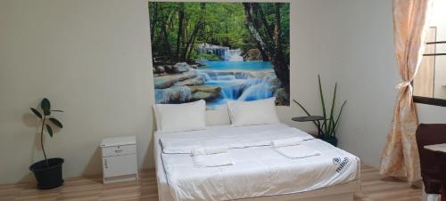 Schlafzimmer mit einem Bett und einem Wandbild mit Wasserfall in der Unterkunft Batikseafood Airport & Room in Ban Bo Sai Klang