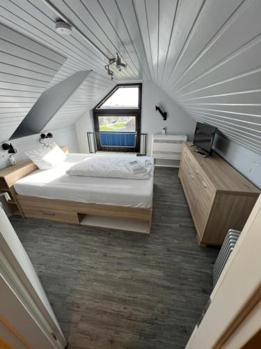 an attic bedroom with a bed and a window at Hotel Tum Stüürmann in Büsum
