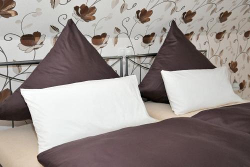 Una cama con almohadas blancas y negras. en Ferienwohnung in Feldmannshof mit Grill und Garten, en Drolshagen