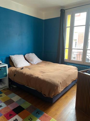 une chambre avec un lit aux murs bleus et une fenêtre dans l'établissement Guest room in a green setting, à Pantin