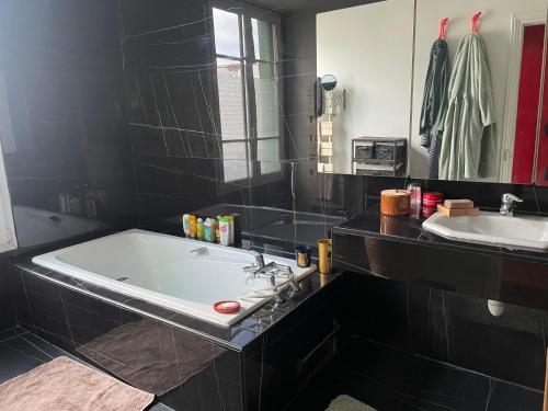 La salle de bains noire est pourvue d'une baignoire et d'un lavabo. dans l'établissement Guest room in a green setting, à Pantin