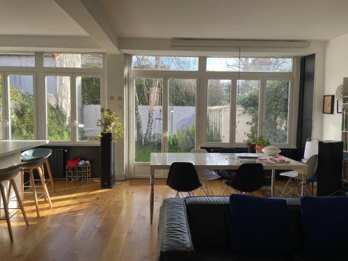 un salon avec une table, des chaises et des fenêtres dans l'établissement Guest room in a green setting, à Pantin