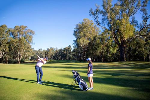 dos personas jugando al golf en un campo de golf en Pat's Place Sun and Lake, en Mulwala