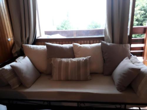 - un canapé blanc avec des oreillers devant une fenêtre dans l'établissement Résidence Bellevue A - maeva Home - Studio 4 Personnes - Budget MAE-6336, à Orcières