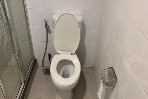 a white toilet in a bathroom with a shower at Hotel Glodok Plaza in Jakarta