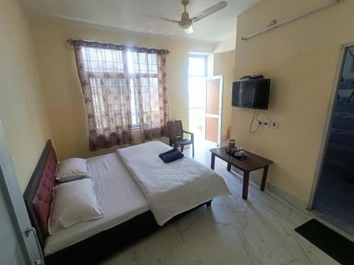 1 dormitorio con cama, mesa y TV en Ramandeep Stays, en Dharamshala