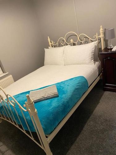 a bed with a blue blanket and white pillows at Malborough - a lovely 3 bed house for short or long-term stays in Derby