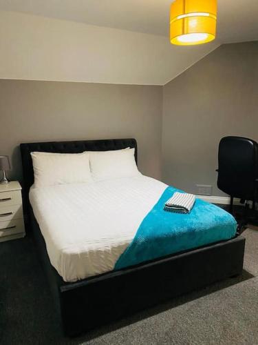 a bedroom with a bed with a blue blanket and a chair at Malborough - a lovely 3 bed house for short or long-term stays in Derby