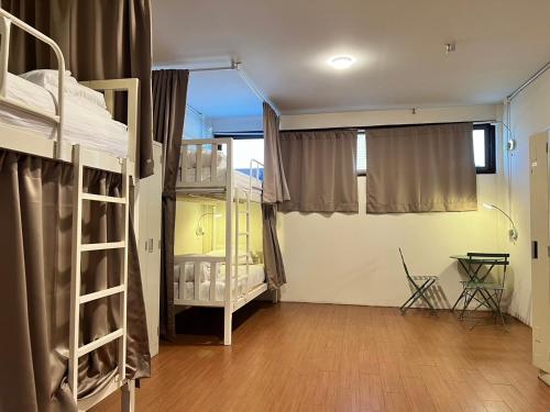 a room with two bunk beds and a table at Allred Hostel Chiangmai in Chiang Mai