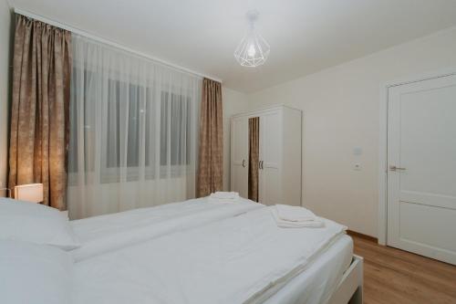 a white bedroom with a bed and a window at CityVibe Residence in Târgu-Mureş