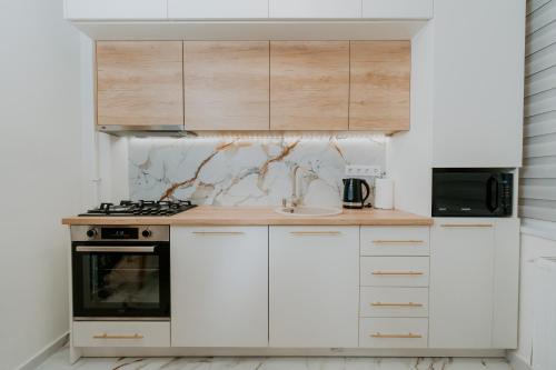 a kitchen with white cabinets and a sink at CityVibe Residence in Târgu-Mureş