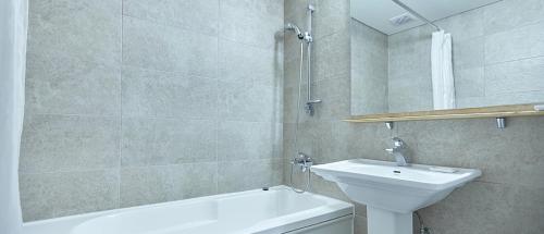 a bathroom with a sink and a toilet and a bath tub at Towerhill Hotel in Busan