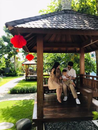 a family sitting on a bench in a gazebo at The Valerian Villa Ubud in Ubud