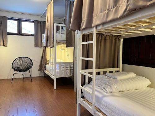 1 Schlafzimmer mit 2 Etagenbetten und einem Stuhl in der Unterkunft Allred Hostel Chiangmai in Chiang Mai