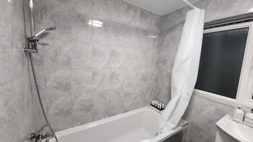 een badkamer met een douche, een bad en een wastafel bij Garland Lovely House with Garden, Watford in Bushey