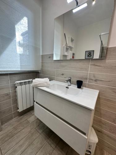 ein Badezimmer mit einem weißen Waschbecken und einem Spiegel in der Unterkunft Coho House Fiumicino in Fiumicino
