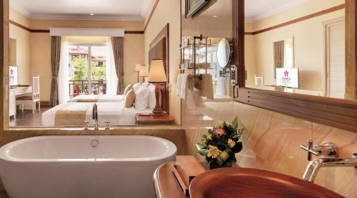 łazienka z wanną i sypialnia z łóżkiem w obiekcie Sokha Siem Reap Resort & Convention Center w Siem Reap