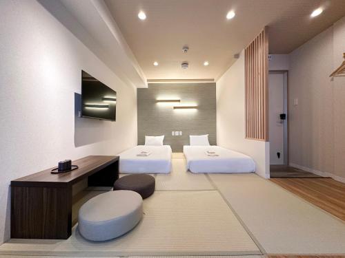 two beds in a room with a desk and two chairs at Osaka Ebisu Hotel in Osaka