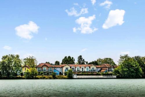 une rangée de maisons sur la rive d'un lac dans l'établissement Résidence Le Hameau du Lac - maeva Home - Appartement 2 pièces 4 personnes - Confort MAE-0524, à Marciac