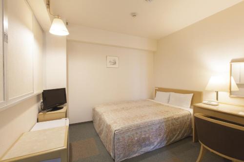 a small room with a bed and a television at Green Hotel Kitakami in Kitakami