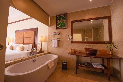 ein Bad mit einer Badewanne, einem Bett und einem Spiegel in der Unterkunft Sokha Siem Reap Resort & Convention Center in Siem Reap