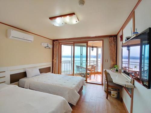 a hotel room with two beds and a desk and a balcony at Bomulsum in Seogwipo