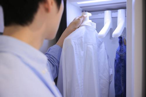 a man is looking at a shirt in a closet at Aank Air Hotel Daejeon in Geochang